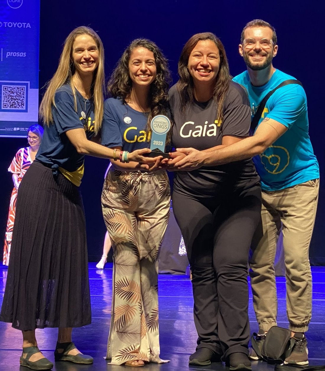 Jéssica Freitas e a equipe da ONG Gaia+ recebendo o prêmio Melhores ONGs 2023 no palco